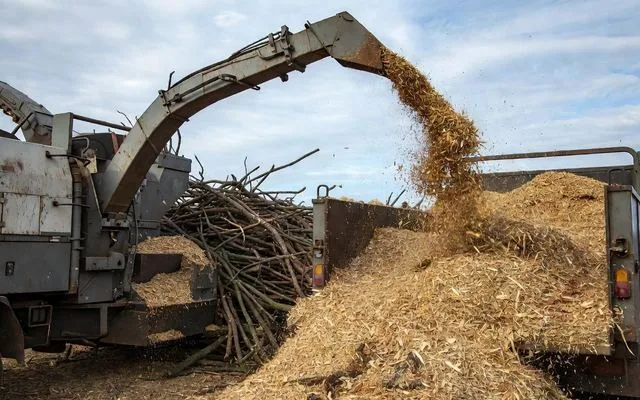 A woodchipper discharging mulch into a truck